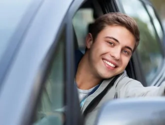 jovem branco de olhos claros faz sinal de joia com o polegar para fora do carro alugado com cnh provisória