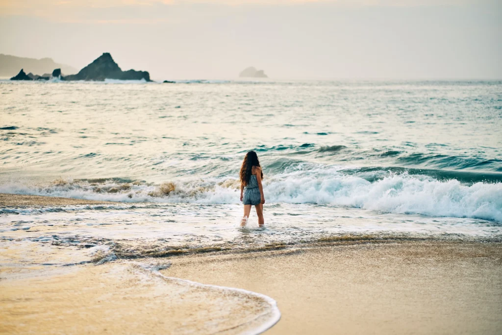 Mujer vestida de negro caminando por Mazunte, una de las mejores playas de México, durante el día.