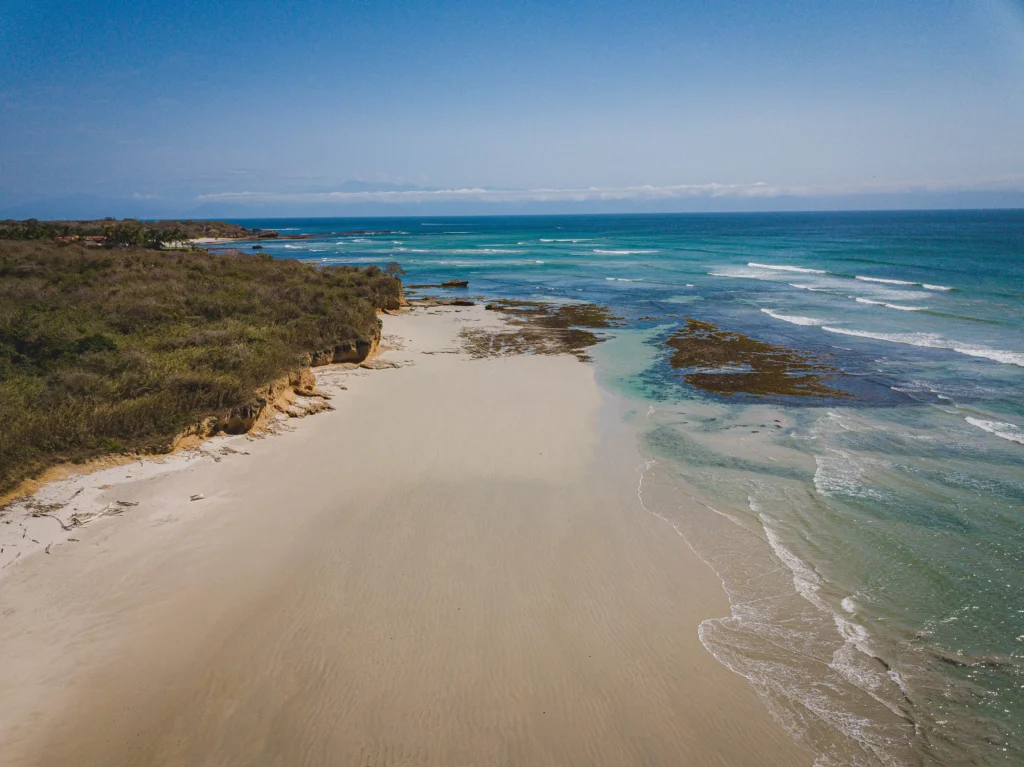 Foto de Punta Mita, una de las mejores playas de México, de arena marrón y mar azul claro durante el día.