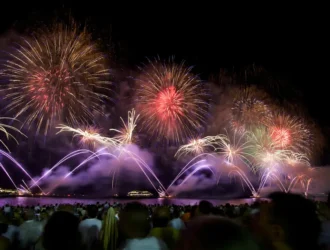 vista da queima de fogos na praia de Copacabana com fogos coloridos, na maioria roxo purpura, vermelho e dourado