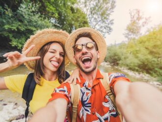 Um casal feliz, com roupas coloridas,tirando uma selfie em um lugar ao ar livre