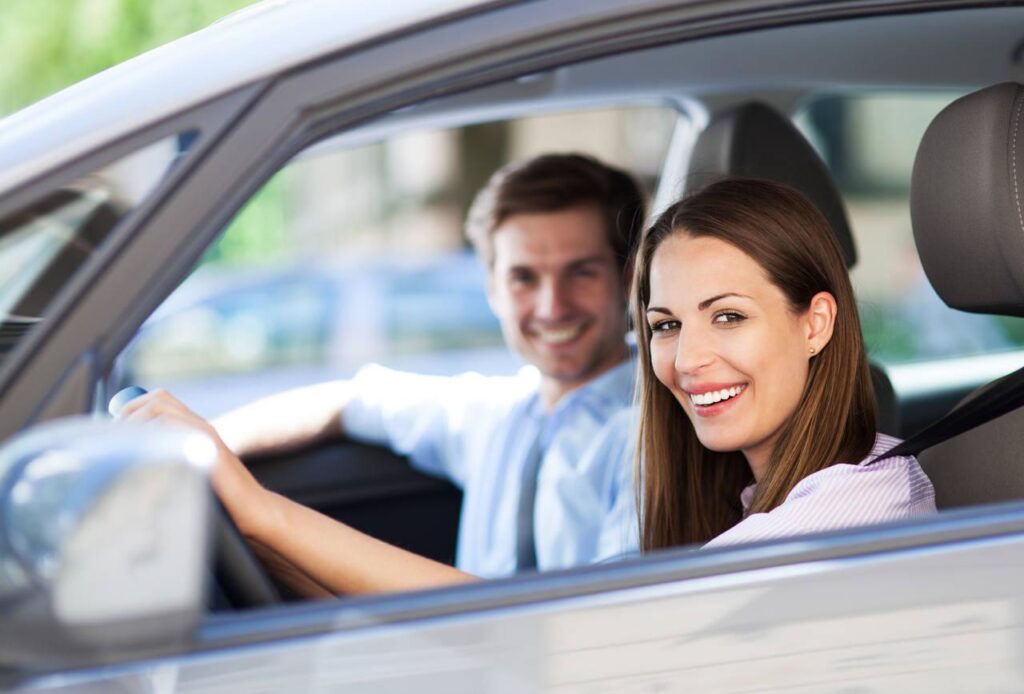 Casal sorrindo dentro de um carro
