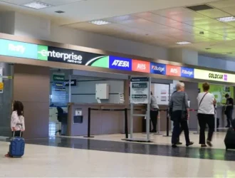 Airport lobby with car rental company stores and people in line
