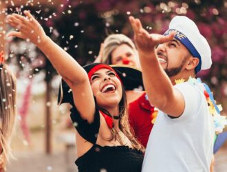 casal jogando confete no ar em uma festa de carnaval de rua