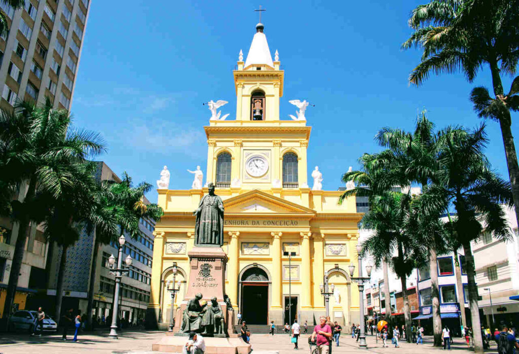 Fachada da Catedral Metropolitana de Campinas durante o dia, com pessoas andando e observando.