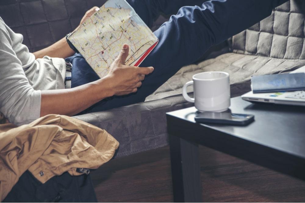 homem deitado observando mapa de viagem