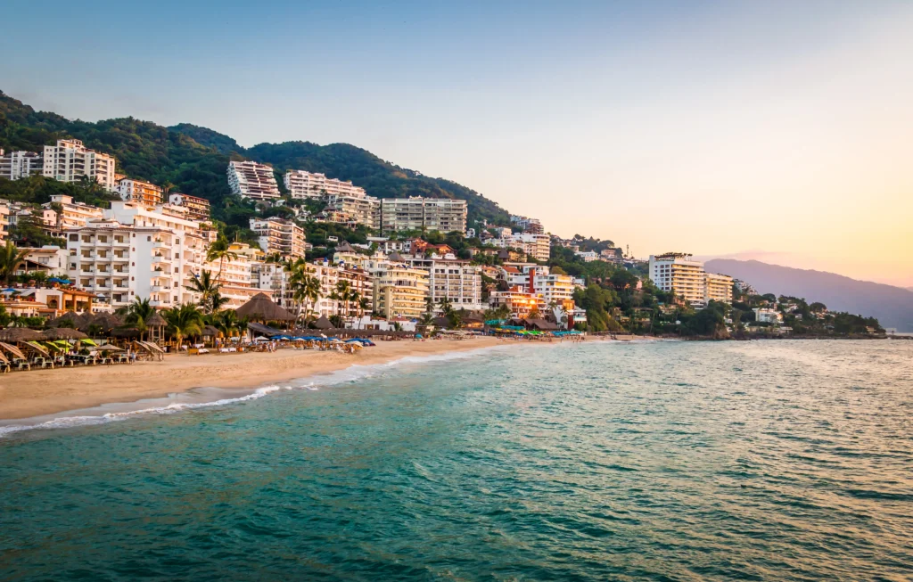 Paisaje de Puerto Vallarta con el mar, la playa y los edifícios al fondo.