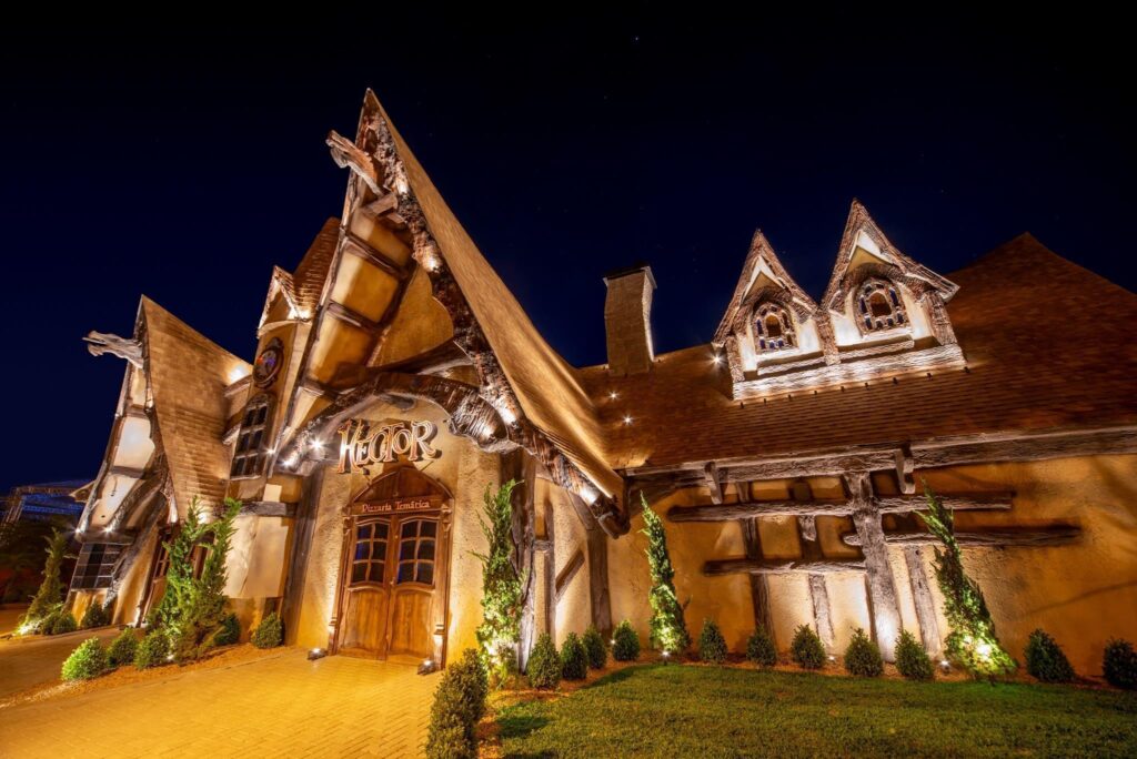 fachada iluminada da hector pizzaria à noite