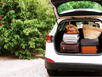 carro branco com porta malas aberto com bagagens