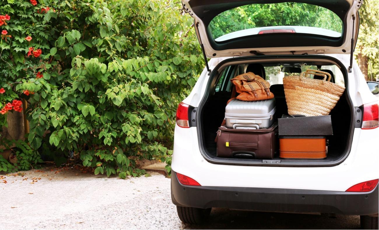 carro branco com porta malas aberto com bagagens