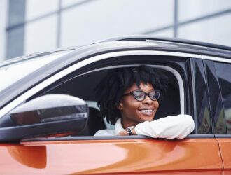 woman inside driver's side of an orange car