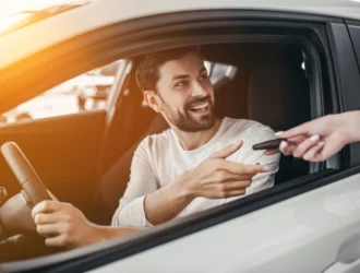 homem de camisa branca dentro de um carro devolvendo as chaves para pessoa ao lado de fora