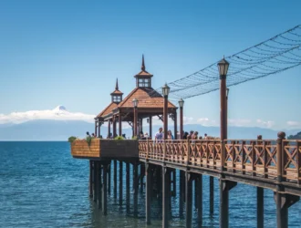 Foto del famoso muelle de Frutillar en un día soleado, con el cielo y el mar azules.