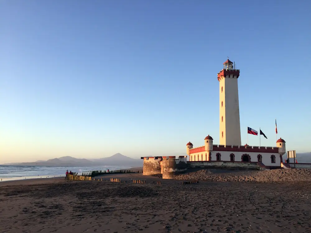 Foto del faro de la serena de lejos, con vista al mar y cielo azul.