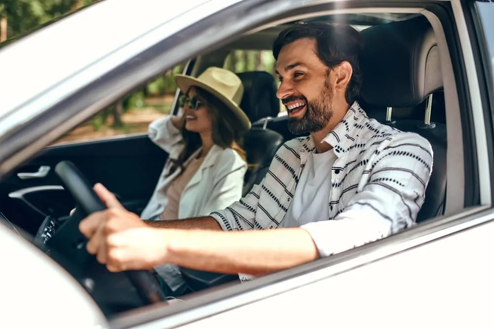Foto de casal sorrindo dentro do carro indo passear.
