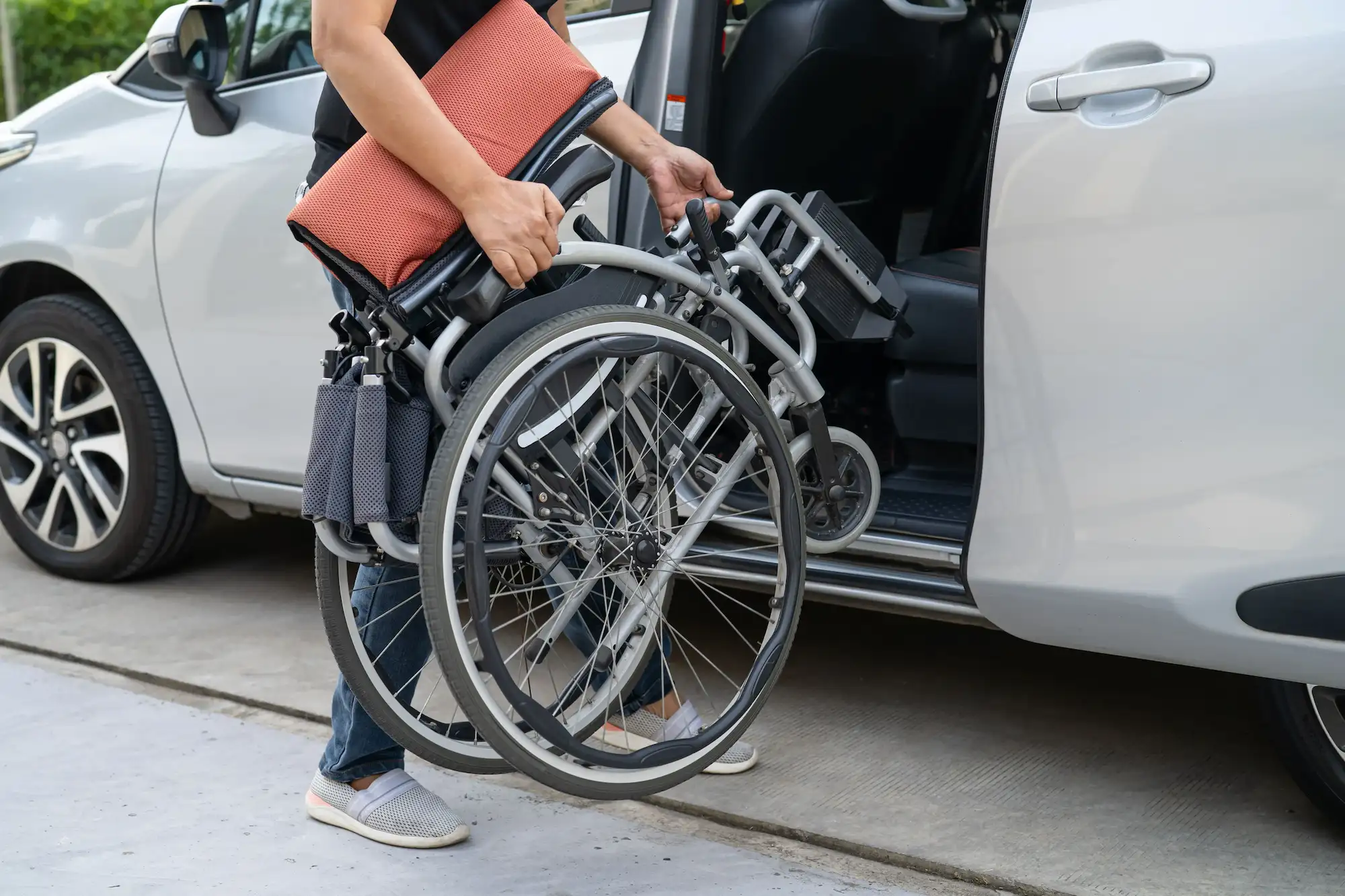 Person putting a wheelchair inside a vehicle.