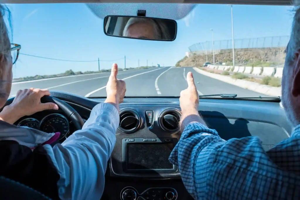 Pareja de ancianos, felices conduciendo por la carretera