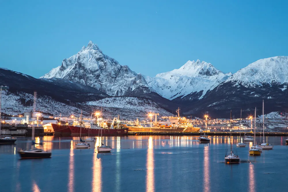 Foto do início da noite em Ushuaia, Argentina, também conhecido como fim do mundo. As montanhas estão cobertas pela neve.