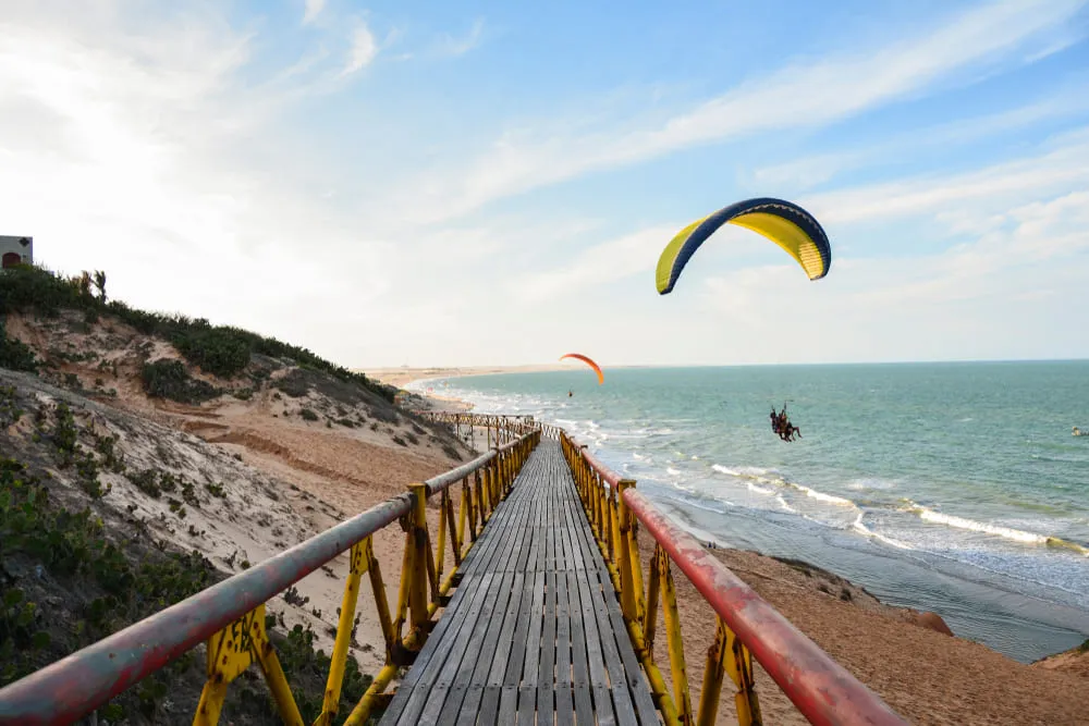Foto da Praia de Canoa Quebrada, em Aracati Ceará. Na foto tem pessoas praticando o Parapente.