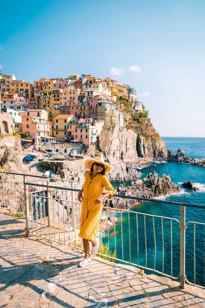 Foto de mulher sorridente na frente de uma das terras de Cinque Terre, na Itália.
