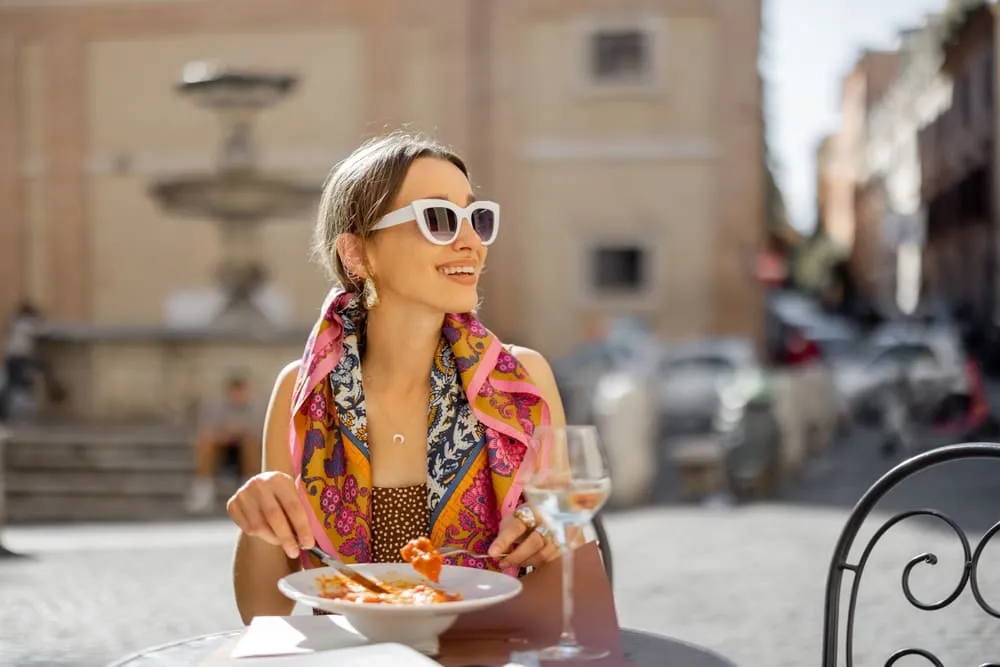 Uma mulher sorridente almoça uma massa tipicamente italiana na praça principal de Florença, na Itália.