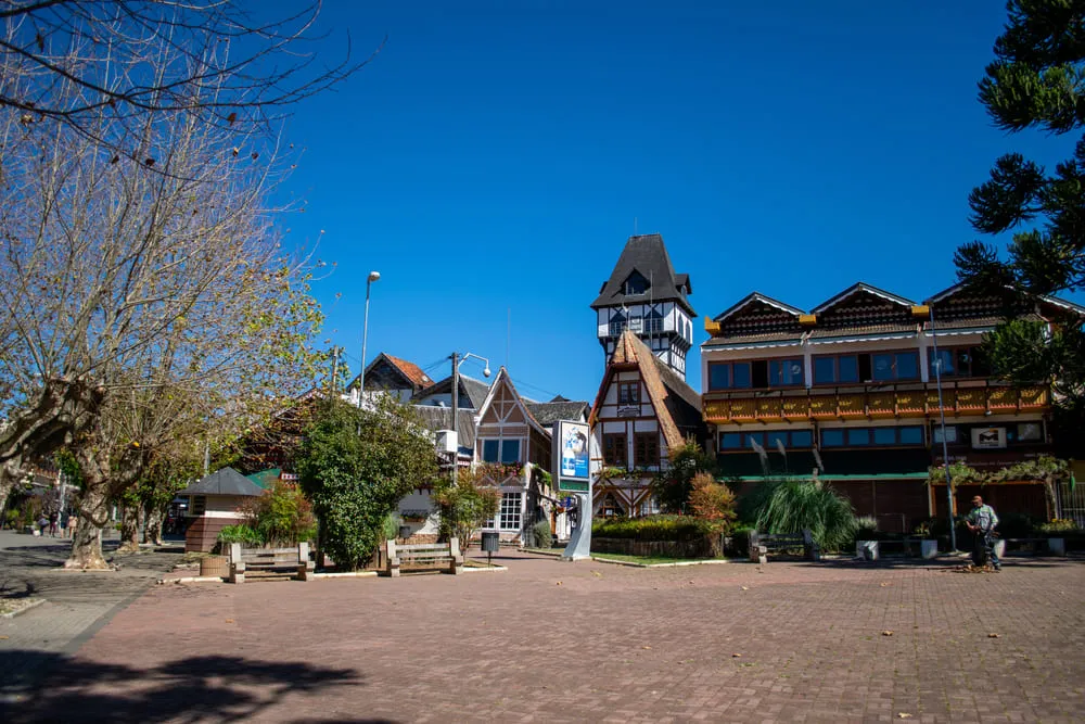 Foto do centro famoso de Campos do Jordão, em São Paulo. A arquitetura no estilo europeu dá todo charme para as casas da foto. O céu está azul.