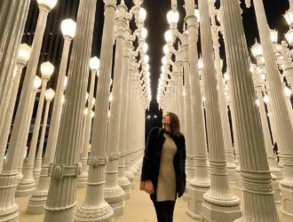 imagem de um salão com centenas de postes de luz brancos, com uma menina posando ao centro