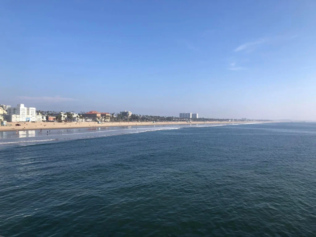 Foto da Praia de Santa Mônica, em Los Angeles. O mar é bem azul e o céu bem claro.