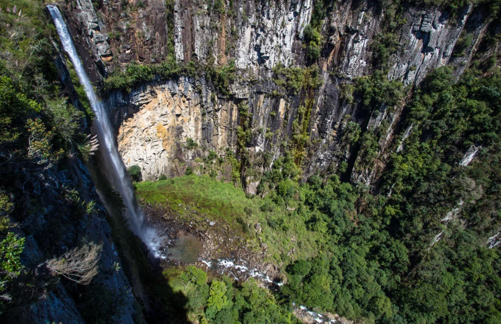 Foto aérea de Urubici na Serra Catarinense. É possível ver a enorme cascata que forma uma cachoeira em meio a natureza e formações rochosas impressionantes.