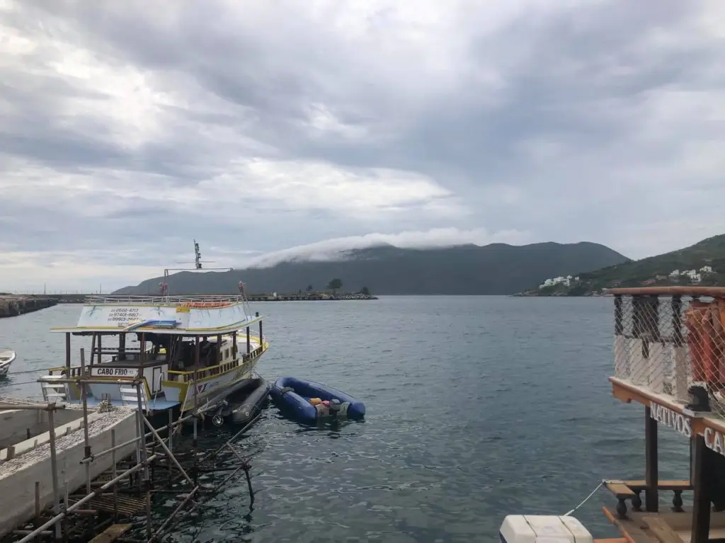 Foto da Praia dos Anjos em Arraial do Cabo. É possível ver um barco estacionado no mar.