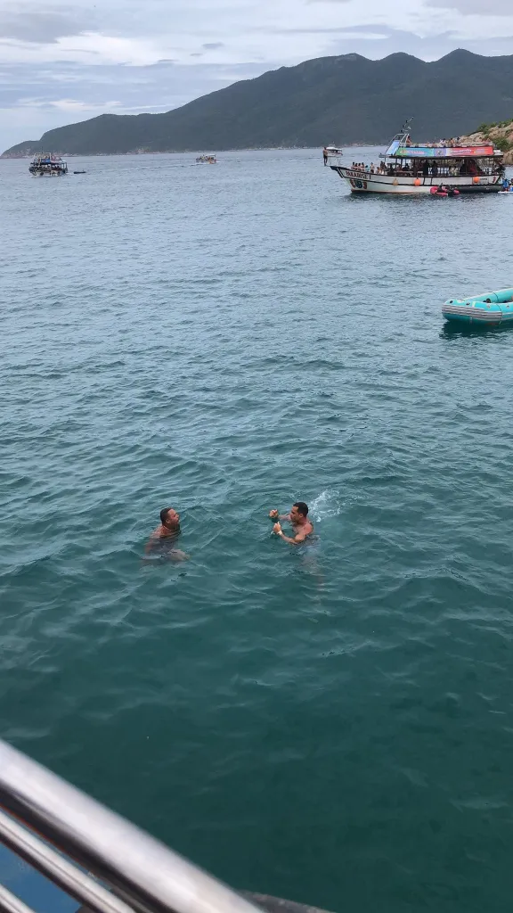 Foto em Arraial do Cabo. A foto foi tirada a partir da vista do passeio de barco realizado na região. O mar é bem azul e algumas pessoas se banham em alto mar.