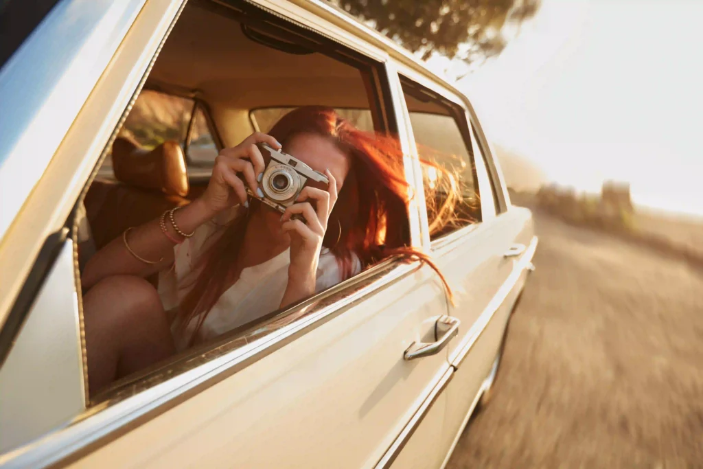 Mujer viajando en auto y haciendo una foto en movimiento