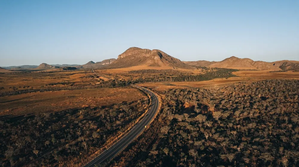 Foto da estrada em Goiás, com a vegetação mais seca ao redor e o céu bem azul.