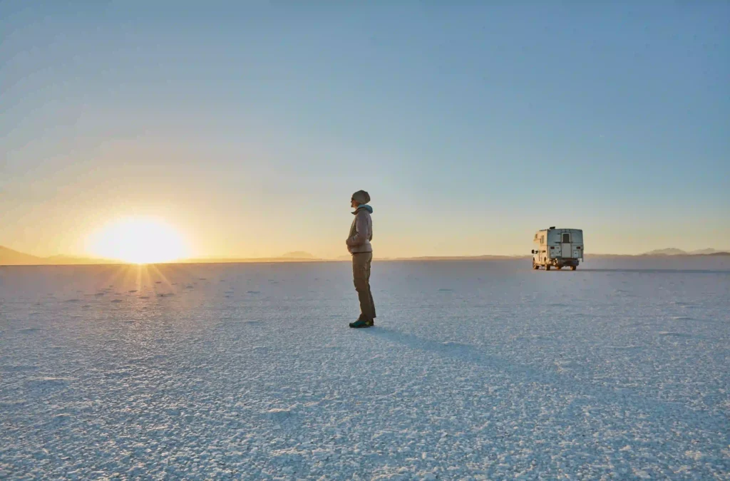 Salar de Bolivia en un dia soleado con una persona disfrutando de la puesta de sol