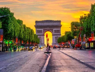 As warmth bathes the iconic Arc de Triomphe in hues of amber and gold, the last rays of the day cast a gentle glow on the intricate carvings. A testament to Parisian grandeur, the silhouette stands proud against the vivid canvas of a sunset sky, whispering tales of history and elegance