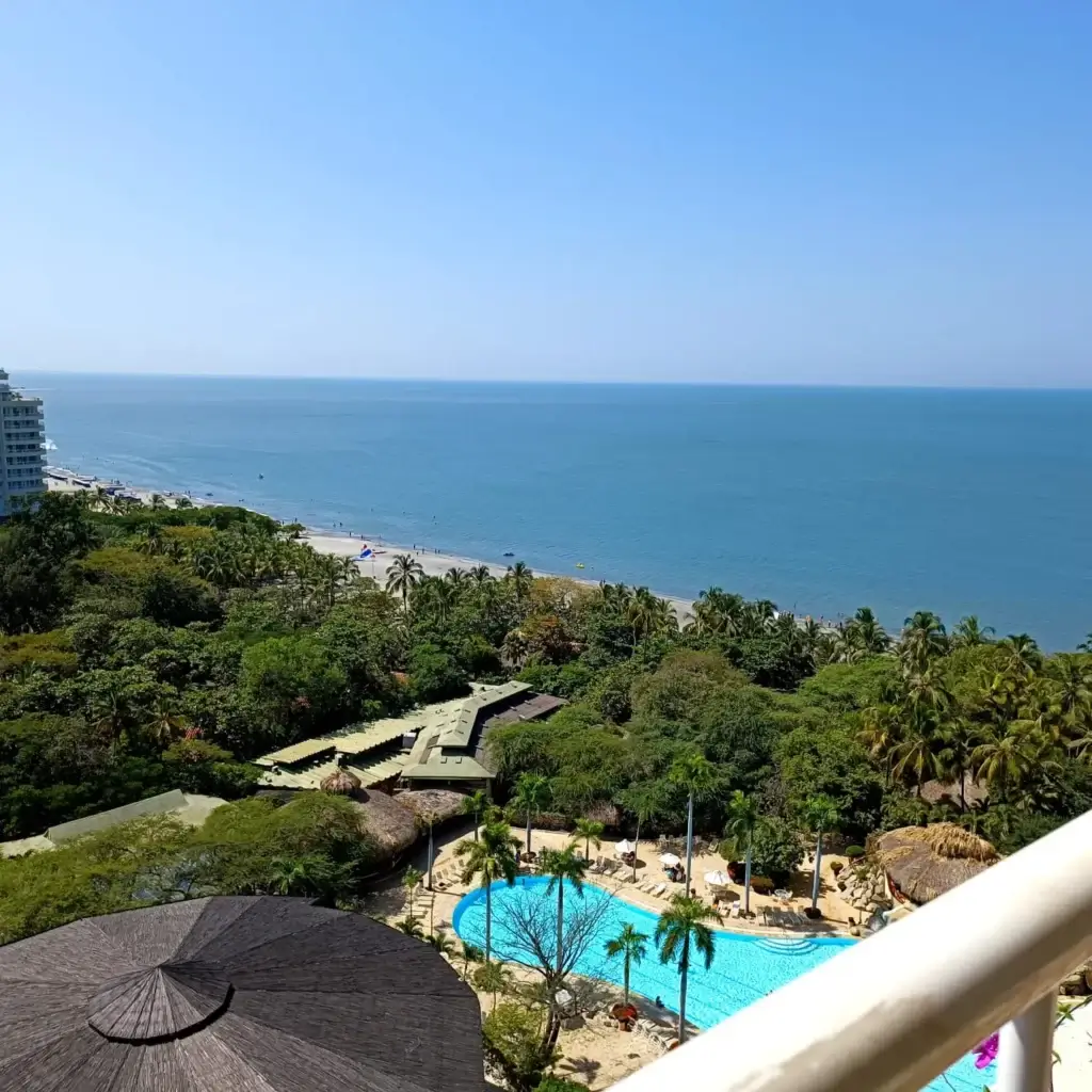 Foto desde arriba del horizonte de Santa Marta, uno de los mejores lugares donde viajar sola por primera vez. El azul del mar se confunde al del cielo y hay mucha vegetación alrededor. 