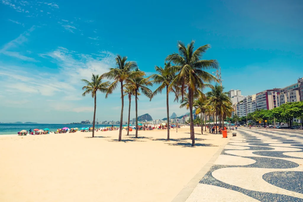 The photo captures the sand and ocean of Copacabana beach, along with the iconic "Calçadão" boardwalk.