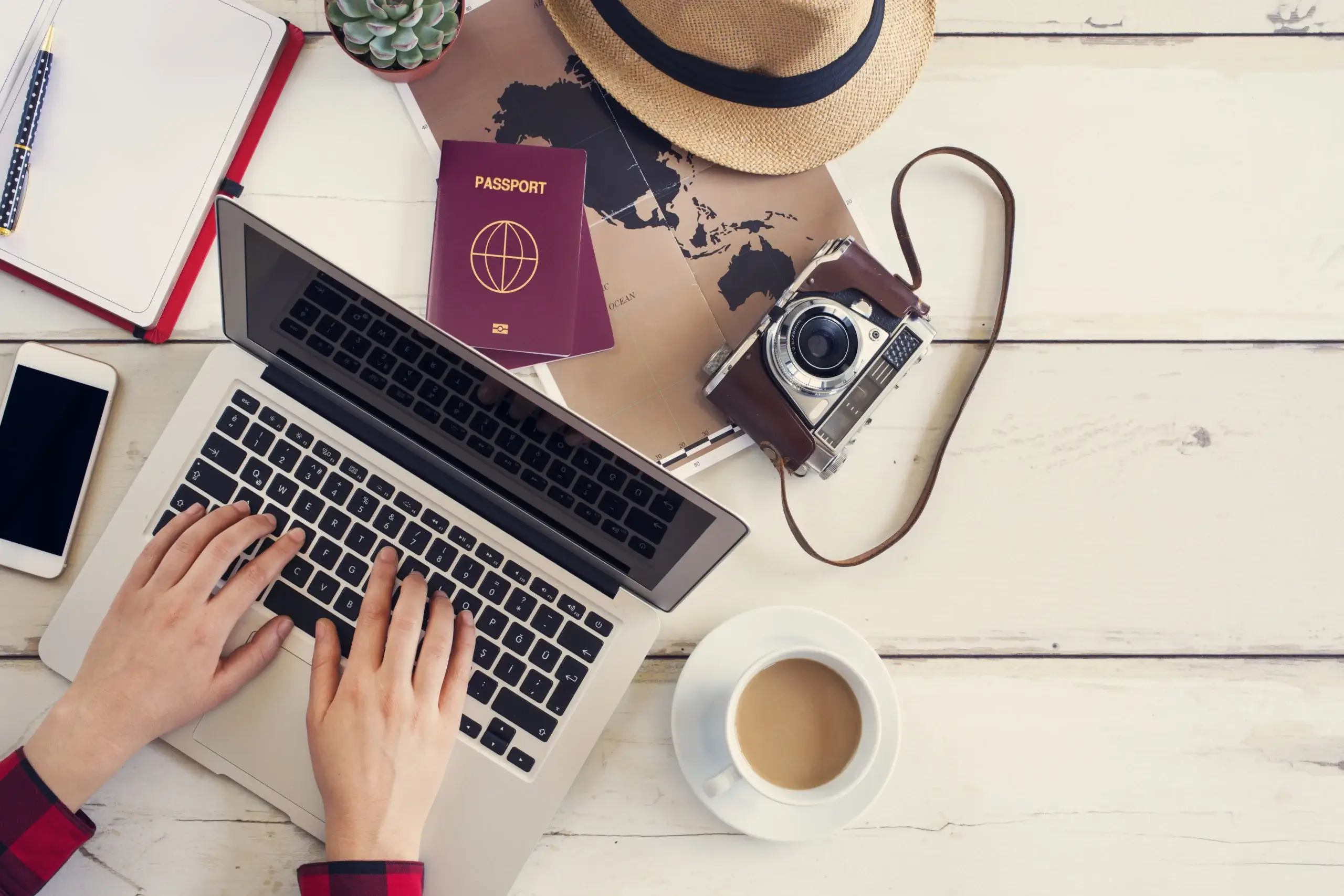 Foto de computador, pasaporte, diario y otras cosas necesarias para aprender cómo hacer un itinerario de viaje.